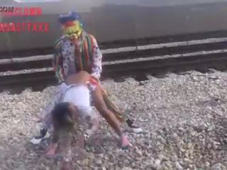 Клоун чука млад дама на влак tracks